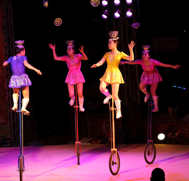 Chinese girls on unicycles catching bowls on their heads Flickr