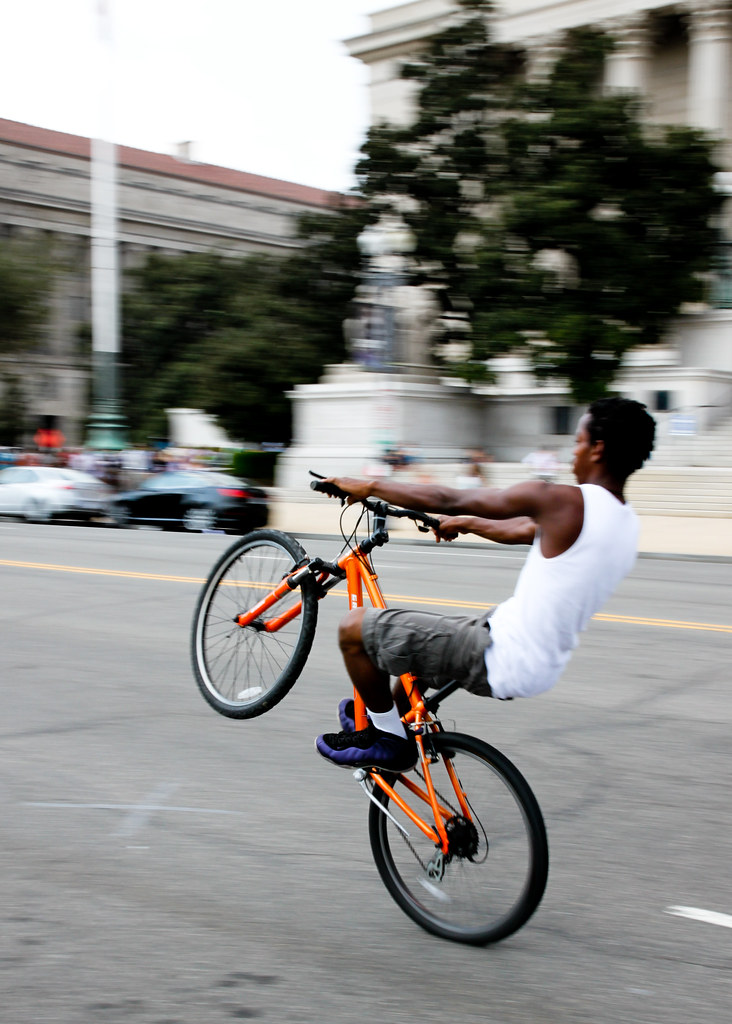 Wheelie A boy pops a wheelie on his bike at the front of A… Flickr