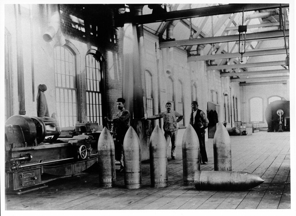 Workers near a group of 12 inch projectiles in the gallery of the new