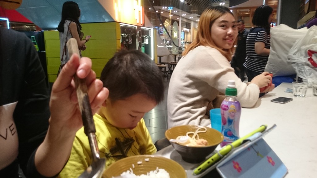 Isaac eating noodles, looking under the table, at Dainty S
