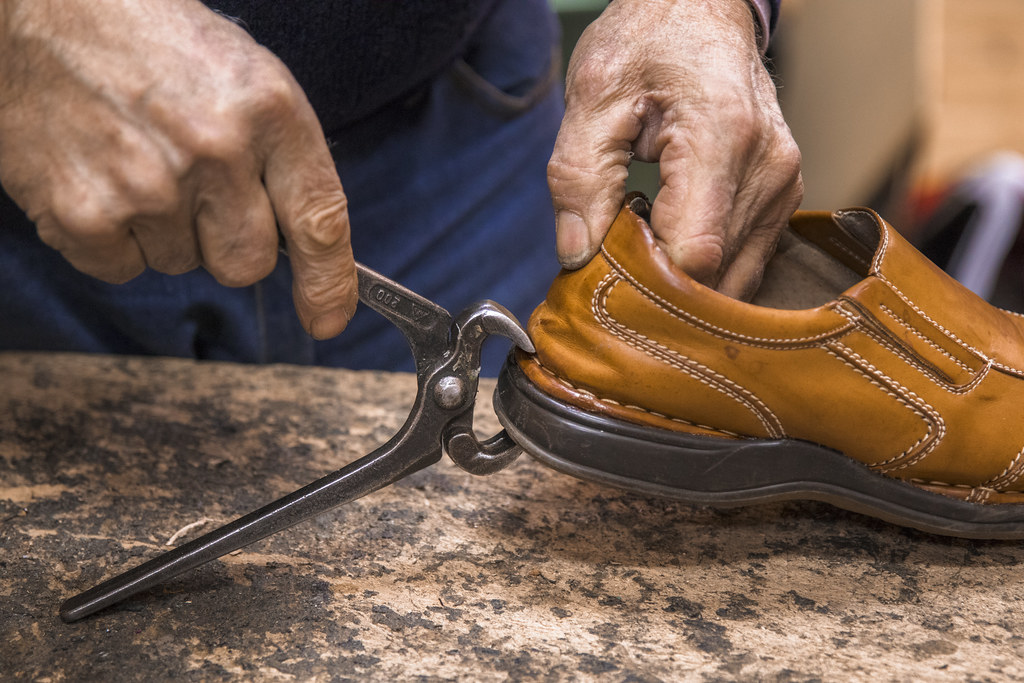 Shoe repairman holding the freshly glued sole in place wit… Flickr