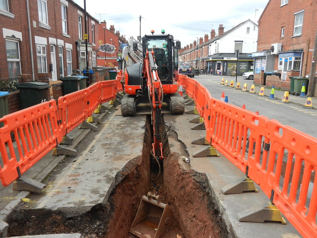 digging a trench for Water road works , small digger Flickr