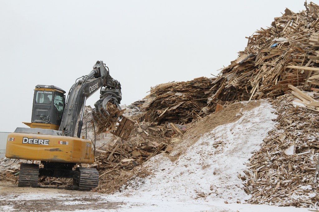 A large grappler sorts and puts wood in the chipper at the… Flickr