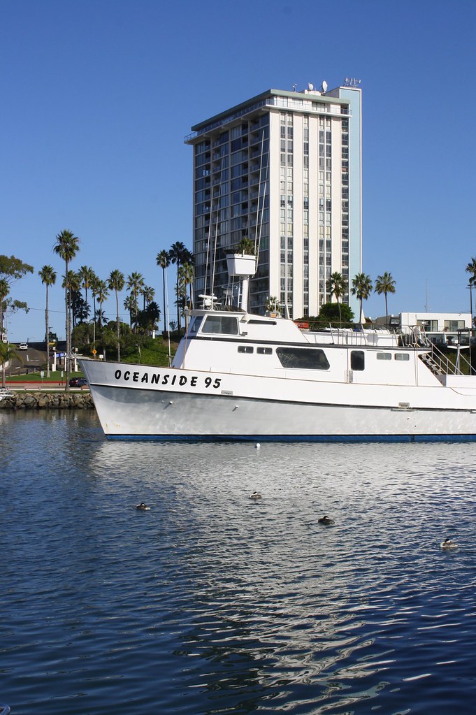 Oceanside 95 Fishing boat with condo building behind it at… Flickr