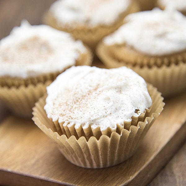 Angled view of apple beer cupcakes on a wood plank.