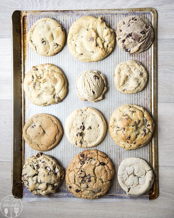 A bunch of different chocolate chip cookies on a cookie sheet. 