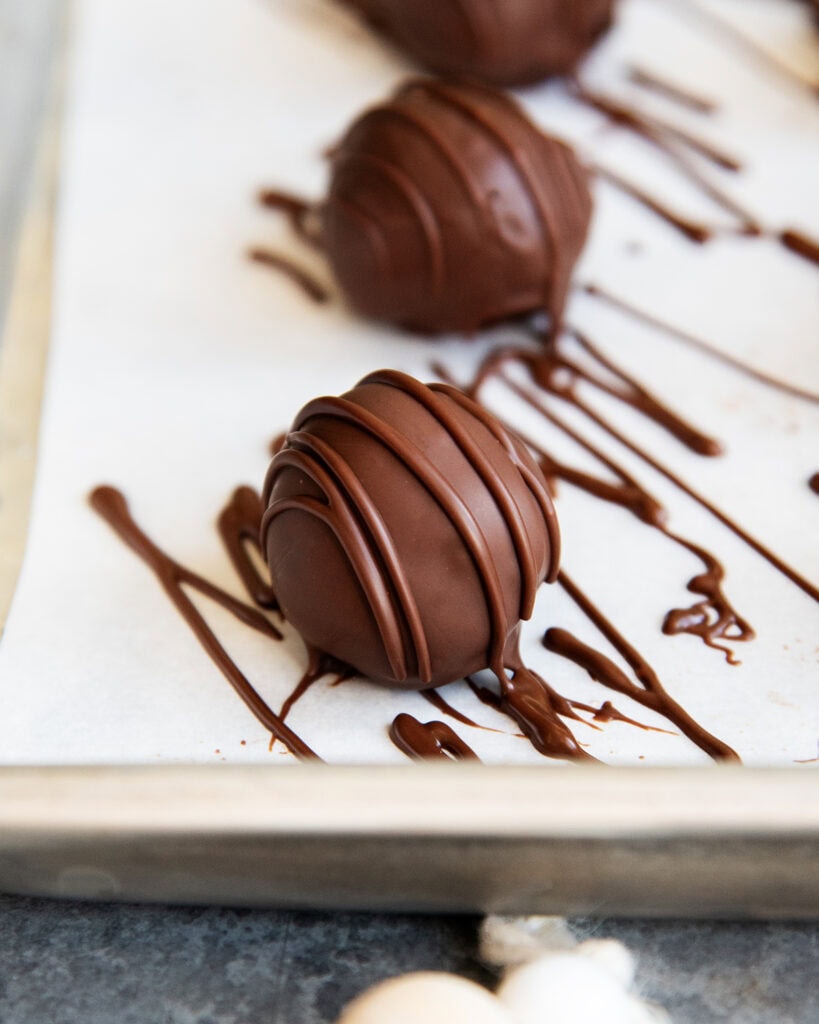 A row of chocolate truffles drizzled with more chocolate on top.
