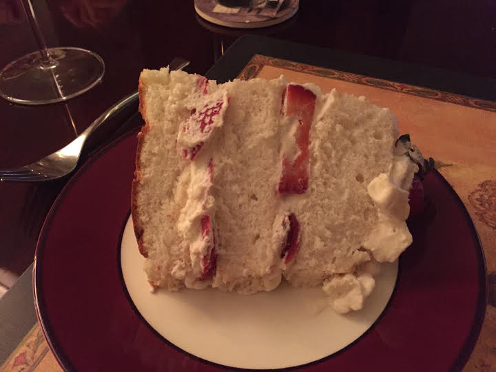 Huge piece of angel food cake with whipped cream and strawberries.