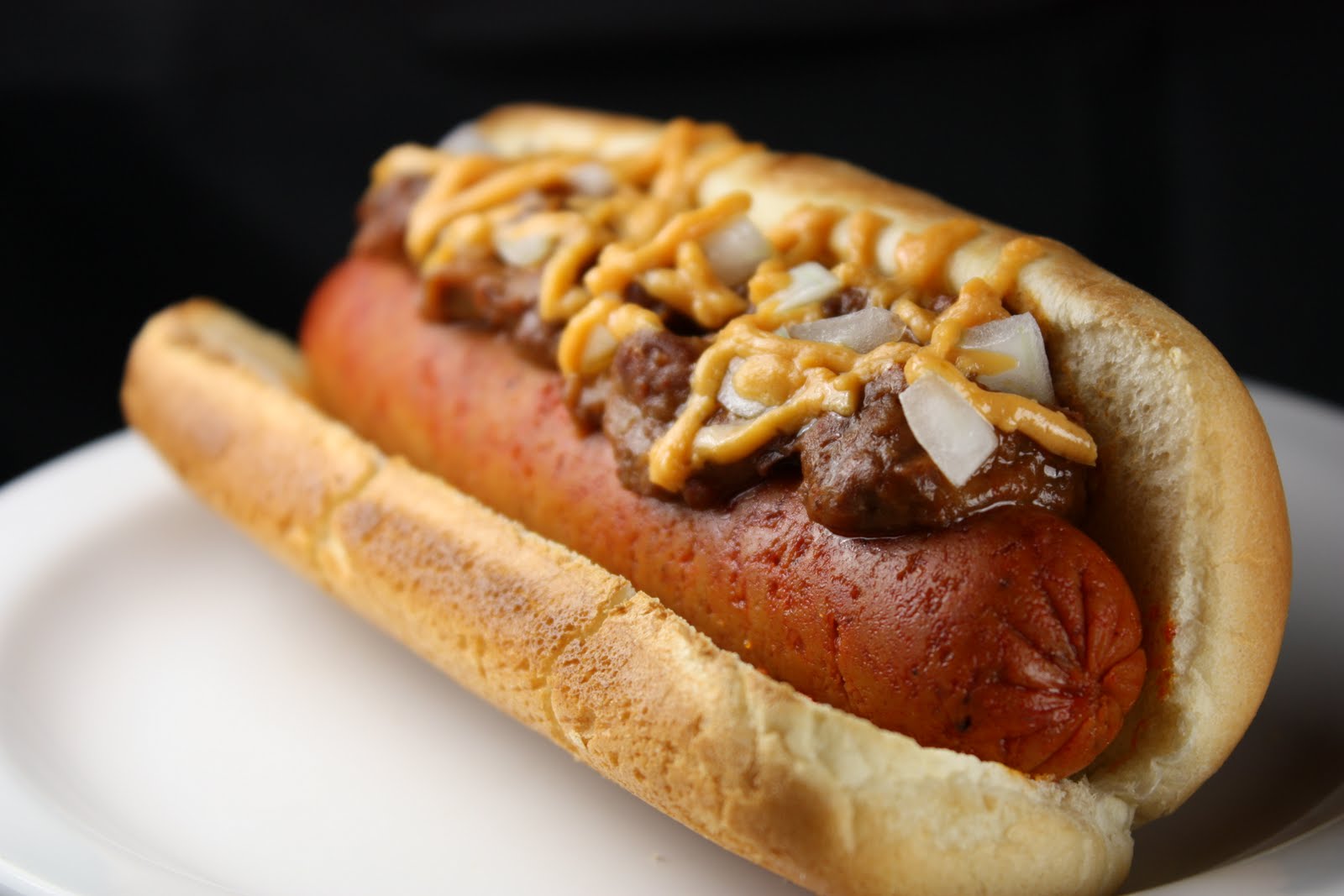 a chili dog with onions and mustard