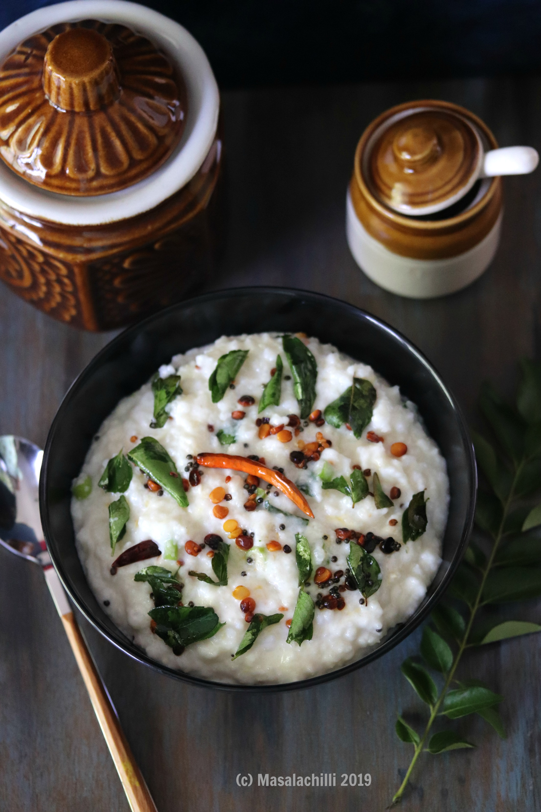 Curd Rice served in a black bowl with a tempering of lentils, mustard seeds, curry leaves and chilies. 