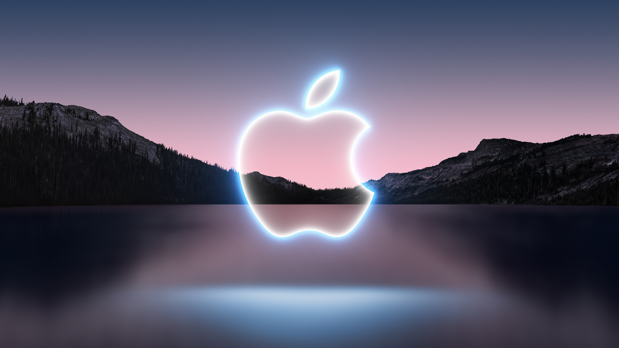 Promotional illustration for the September 14 iPhone 13 event showing a glowing Apple logo outline set against lake scenery shot in the dusk