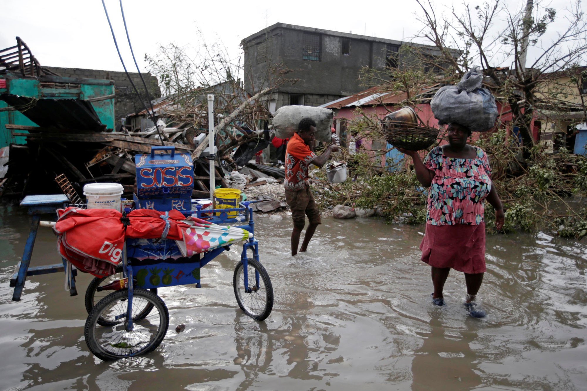 Residents amble through a flooded area after Hurricane Matthew in Les