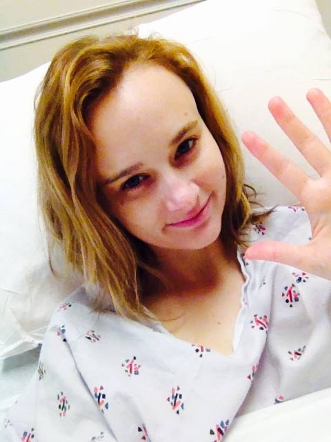 Picture of a woman in a hospital gown waving at the camera.