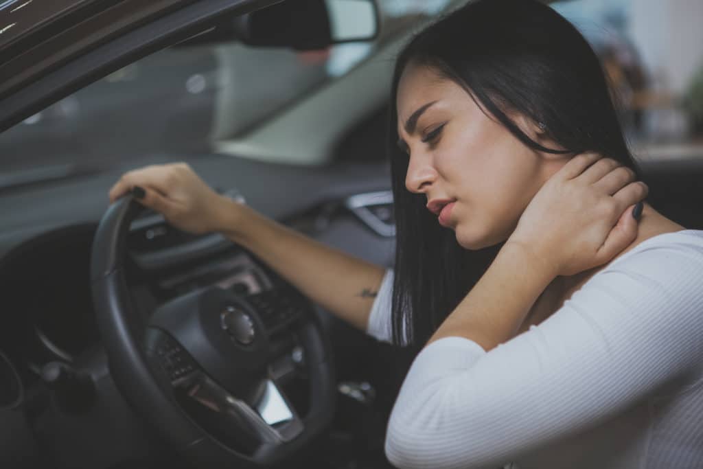 Beautiful young woman rubbing her neck, feeling sore after long drive