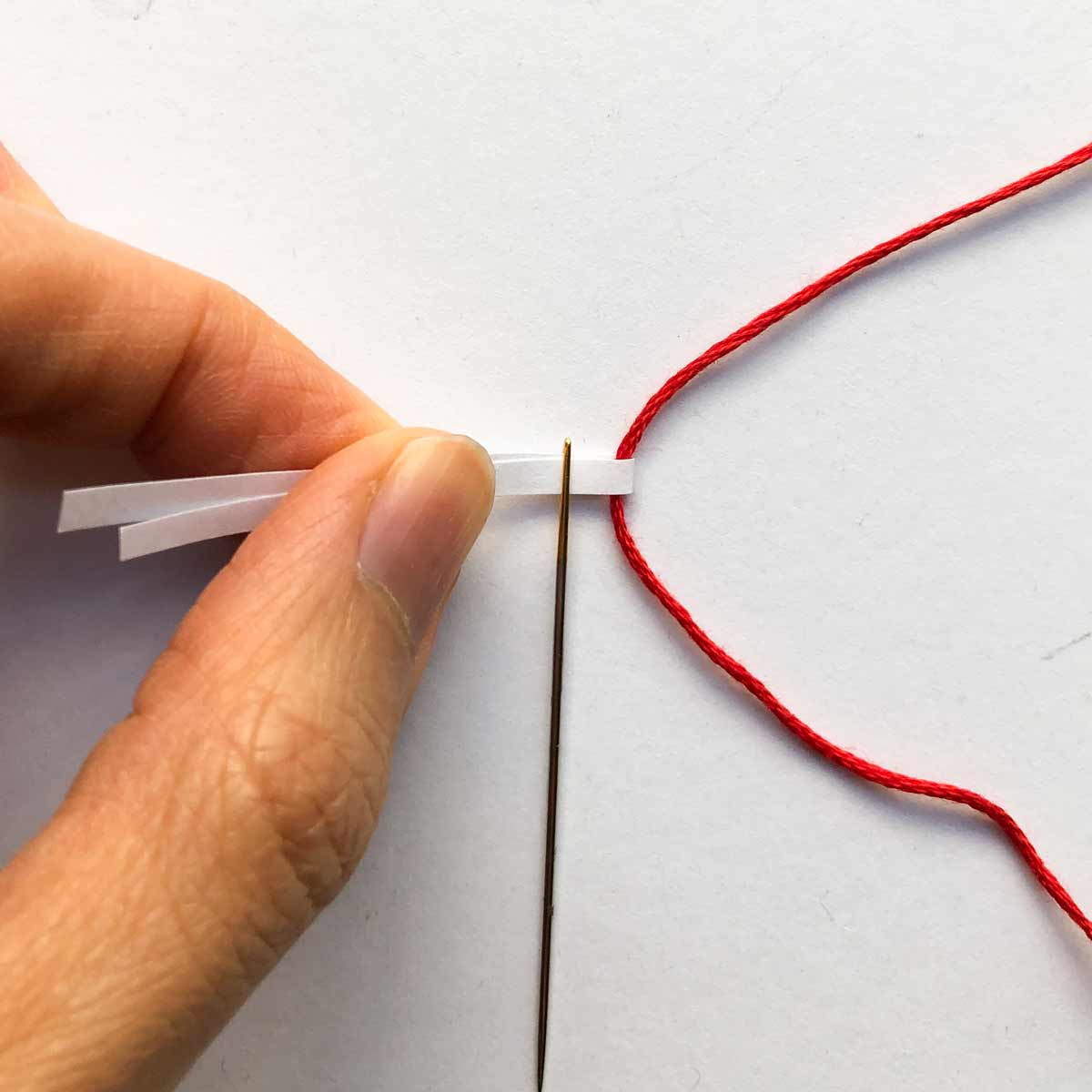 Pulling thread through paper needle threader