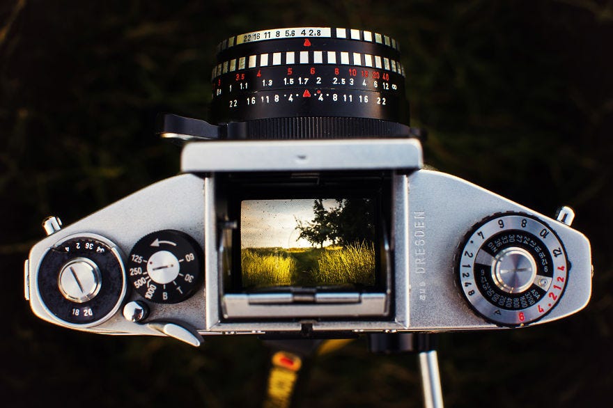 Photographer shoots the world trough the viewfinder of an old film camera