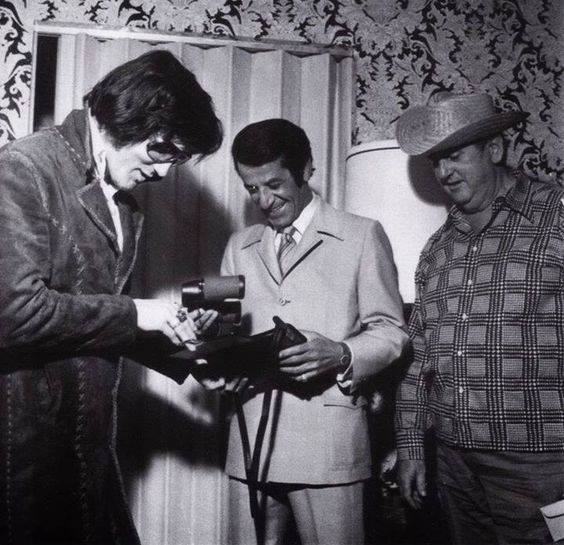 Alex Shoofey presents Elvis Presley with a gift of appreciation at the International Hotel in 1972 while Colonel Tom Parker looks on. Photo Credit: Wikipedia Commons 