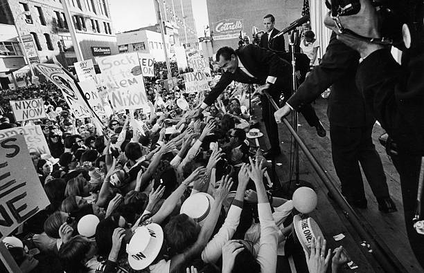 Republican presidential candidate Richard Nixon (1913 - 1994) leans over a railing from a wooden stage during a campaign appearance as people in the front of the crowd reach out their arms to shake his hand, Denver, Colorado, September 25, 1968. Among the visible signs among the crowd are ones that read, 'Sock it to 'em, Nixon,' 'Nixon in November,' and 'Nixon Now.'
Photo Credit: Hulton Archive/Getty Images