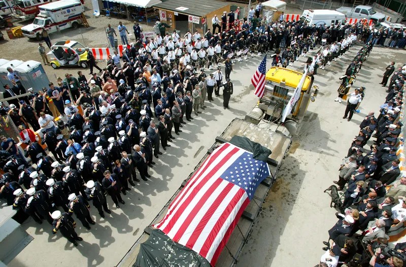 On May 30, 2002, the Last Column was removed from the World Trade Center site on the flatbed truck in a public, televised ceremony. Thousands of people attended including family and friends of victims, members of the armed forces, dignitaries, and rescue, recovery, and relief workers. An honor guard escorted the column from the site. Police and Fire Department buglers played "Taps," while bagpipers and drummers performed "America, the Beautiful." Photo Credit: Associated Press