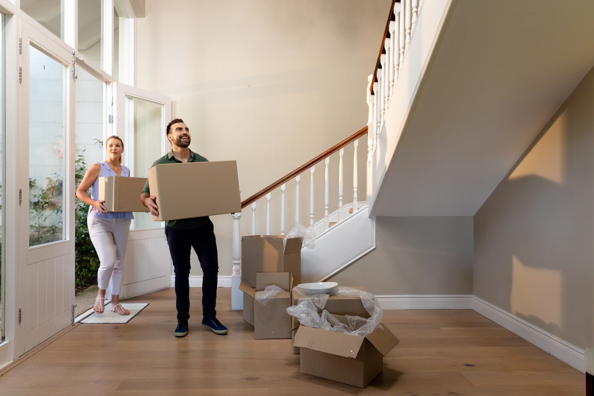 Couple moving boxes with staircase in the background to illustrate how to move when you have stairs