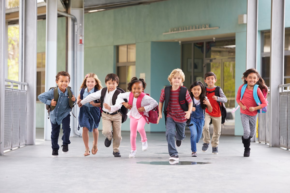 Group of diverse children running towards camera after school has been dismissed to illustrate the concept of moving schools