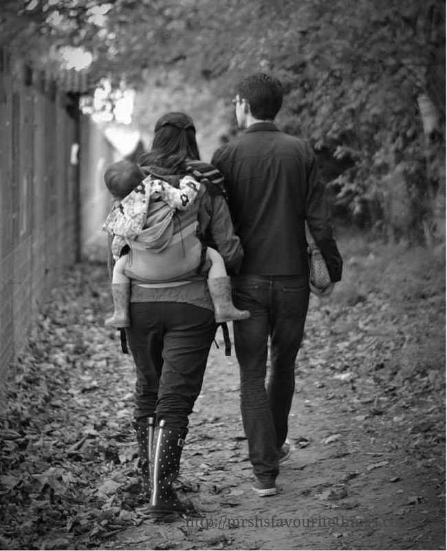 http://mrshsfavouritethings-com.stackstaging.com A black and white photo of a man and his wife and his daughter walking away from the camera_ the wife is baby wearing her toddler daughter on her back in a Lenny Lamb toddler ergo carrier in Caffe Latte Lace__baby wearing love_Mrs H's favourite things