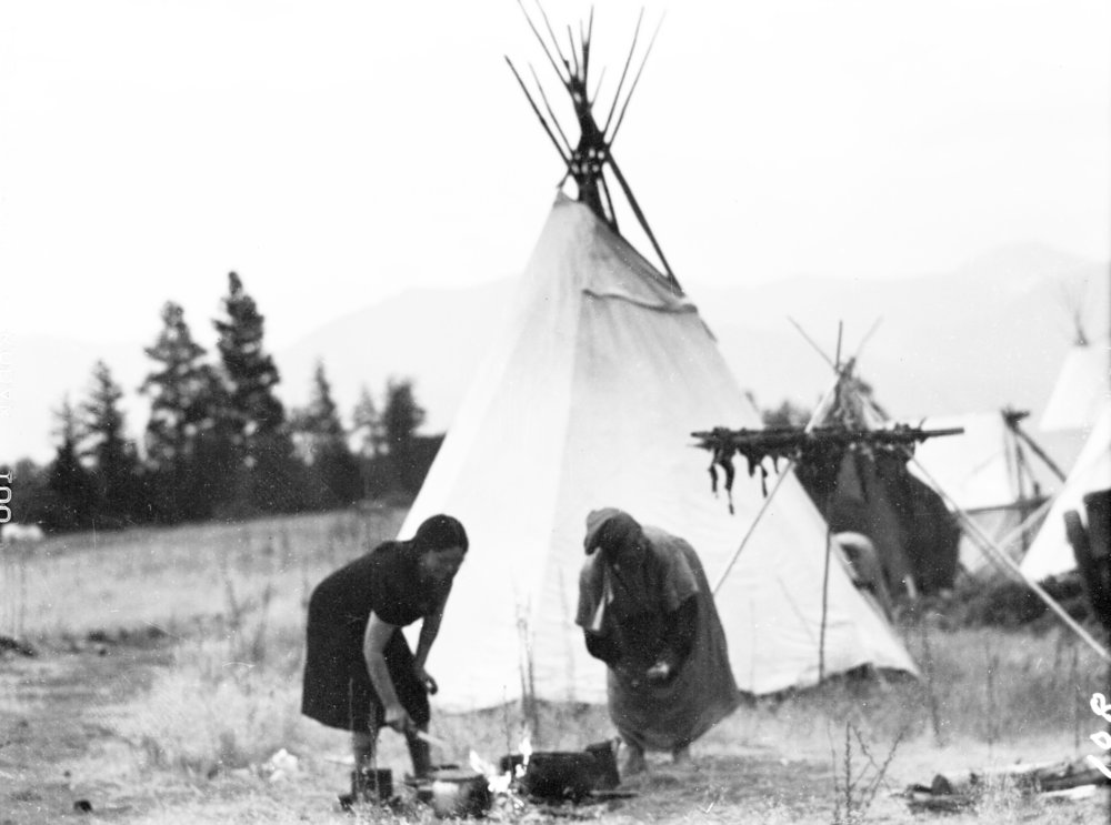 [Two Salish women bent over cooking fire, Arlee, Montana]. Montana