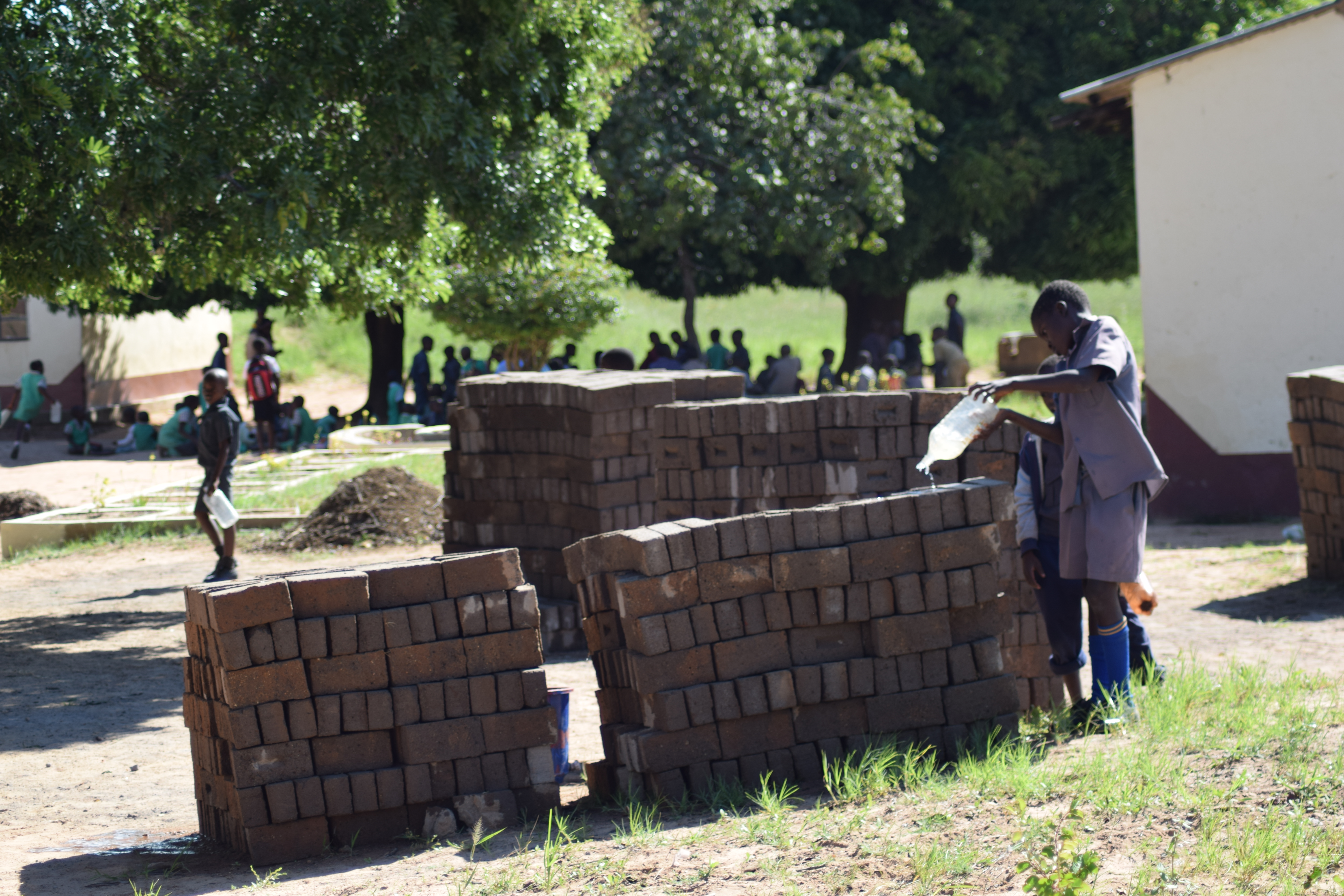 Boy watering bricks for reconstruction work