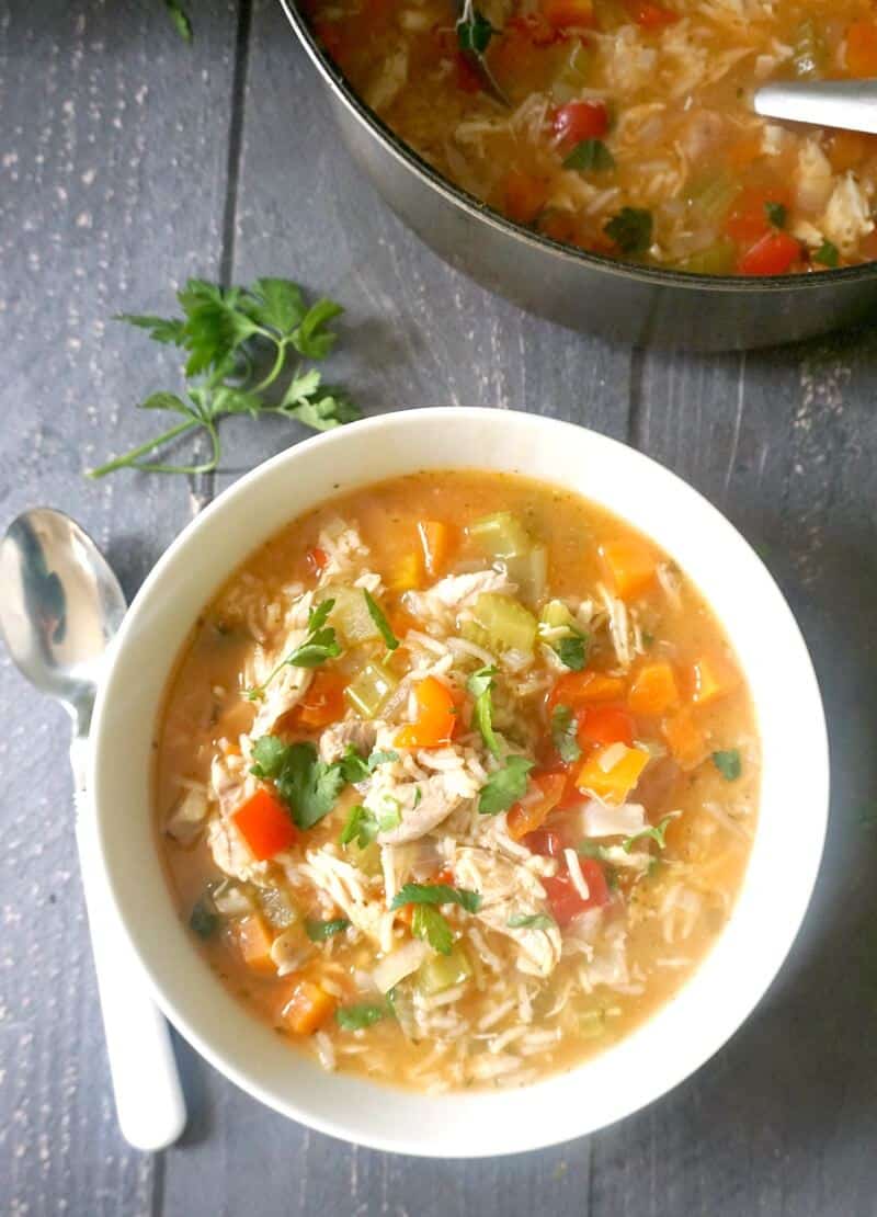 Overhead shoot of a white bowl with turkey and rice soup and a pot of soup next to it