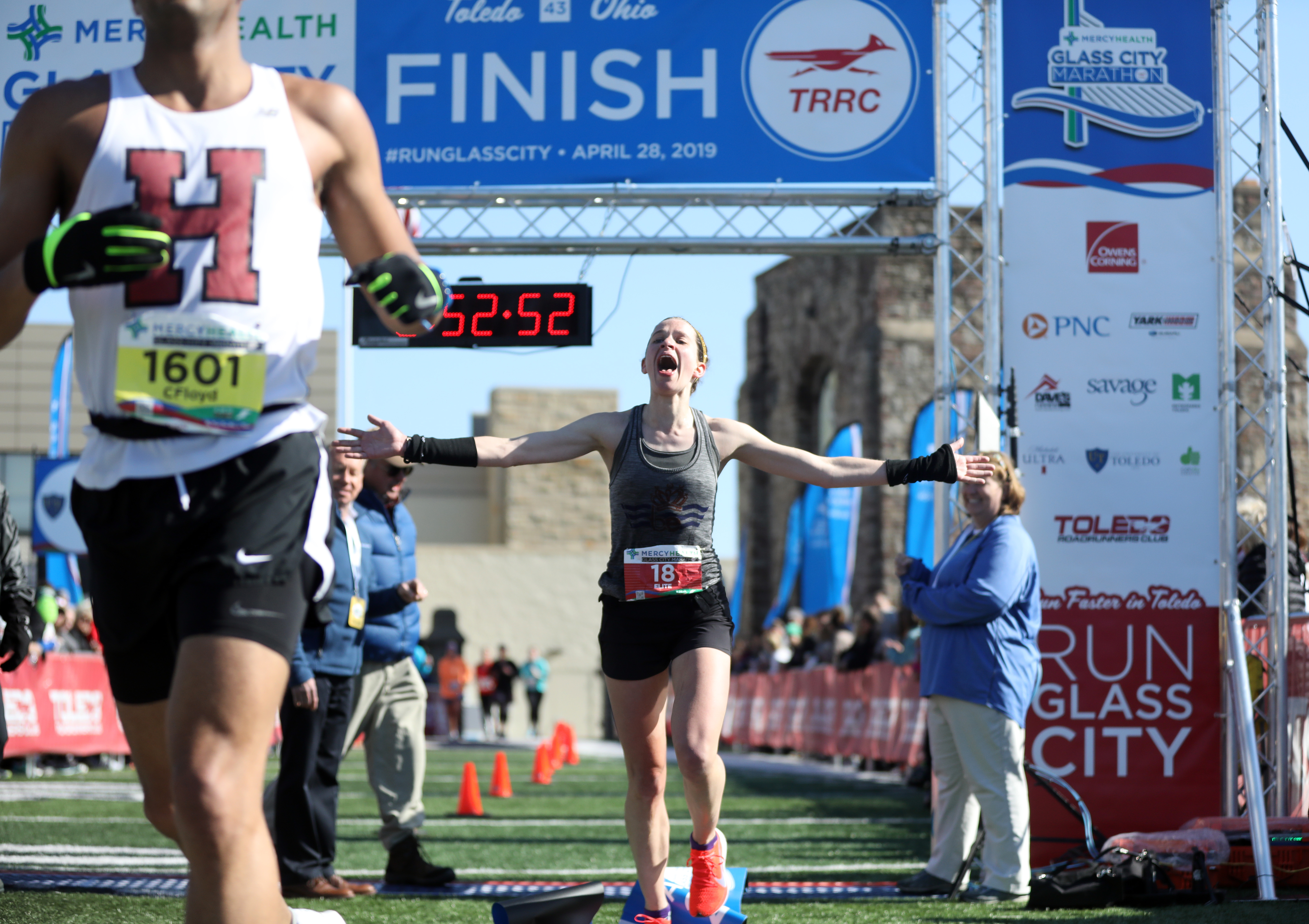 Women's marathon winner Amy Manning, of Cincinnati, right, reacts as Christian Floyd, of Columbus, runs through the finish ribbon at the Glass Bowl meant for the women's marathon during the Mercy Health Glass City Marathon in Toledo on Sunday, April 28, 2019. THE BLADE/KURT STEISS