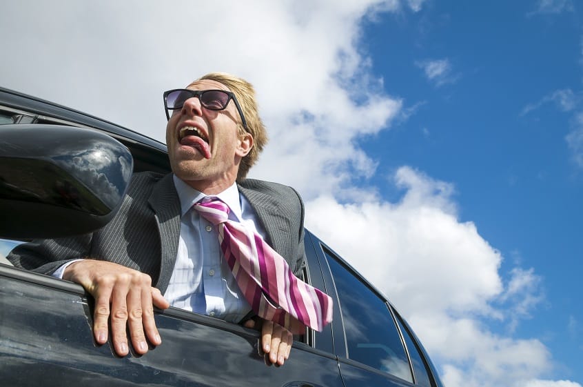 Excited businessman traveling in a car hanging out the