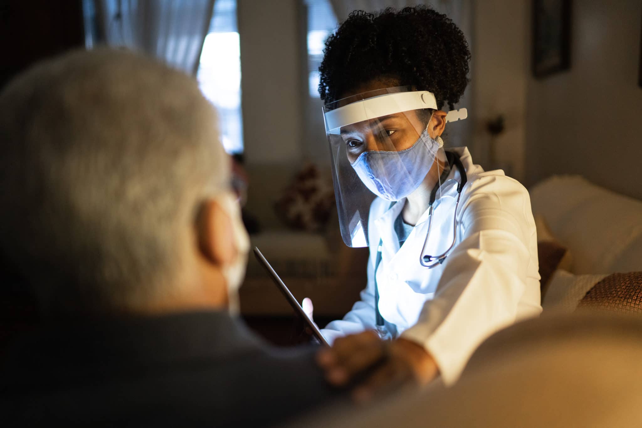 Female Doctor Visiting Her Patient At His Home Appointment With Digital
