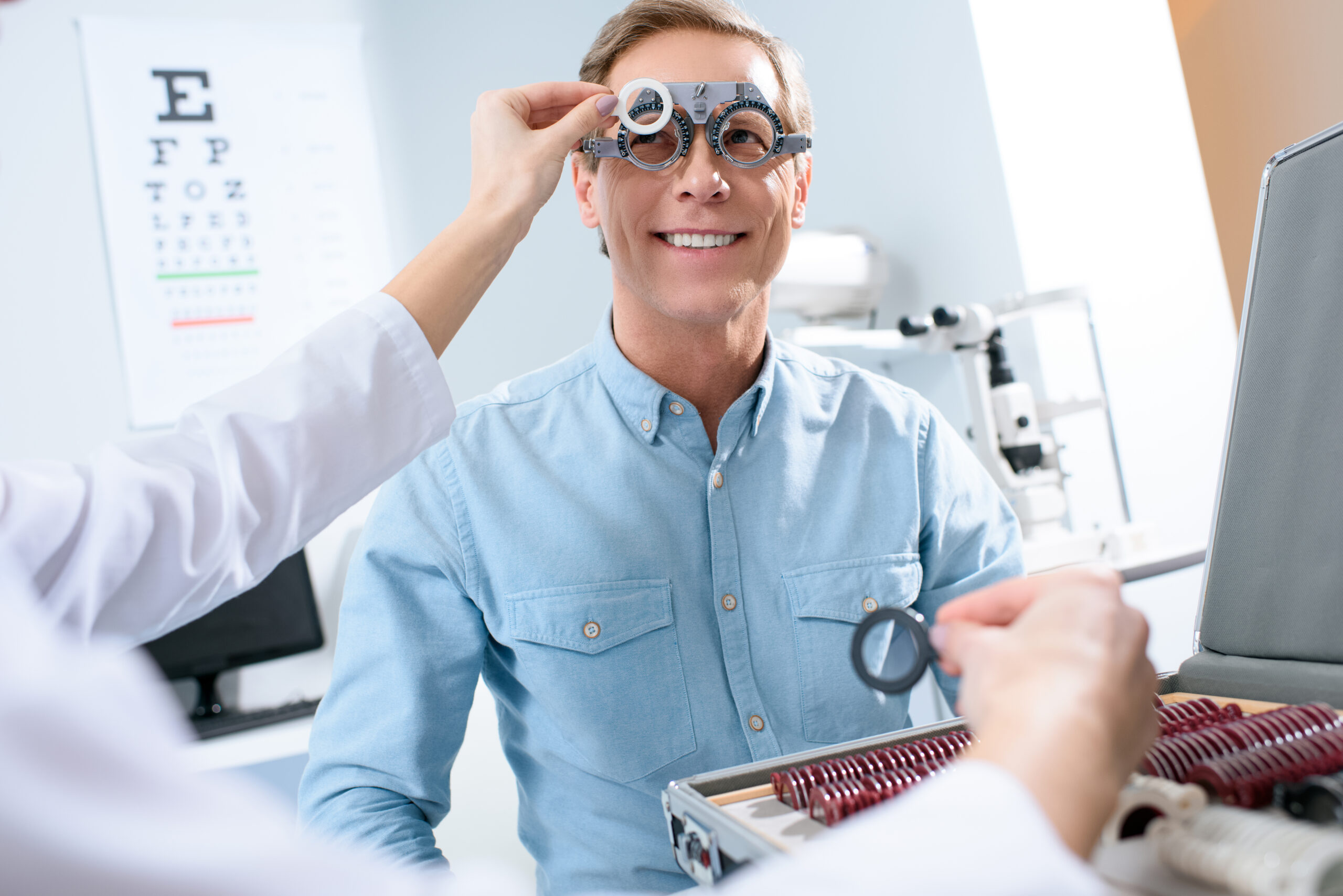 ophthalmologist examining middle aged man eyes with trial frame