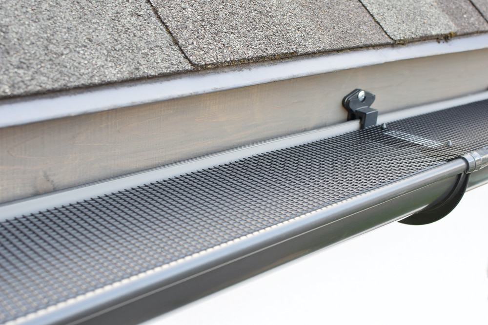 Plastic guard over new dark grey plastic rain gutter on asphalt