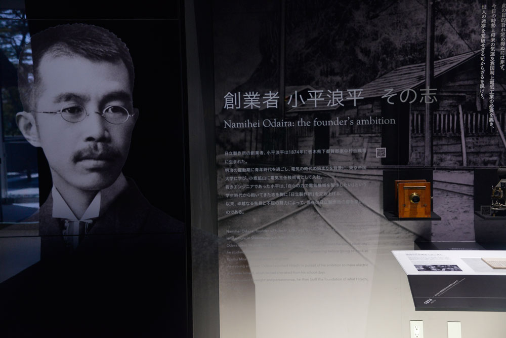 顔写真がガラスに張り付いていますね。キャプションには 日立製作所の創業者、小平浪平は1874年に栃木県下都賀郡家中合戦場に生まれた。 明治の躍動期に青年時代を過ごし、電気の時代の始まりを背景に、東京帝国大学に学び、小坂鉱山に電気主任技術者として入社。 若きエンジニアであった小平は、「自らの力で電気機械を製作したい」という学生時代から抱いていた志を胸に「日立製作所を立ち上げる」。 以来、卓越なる先見と不屈の努力によって、現在の日立製作所の礎を築いたのである。とあります。