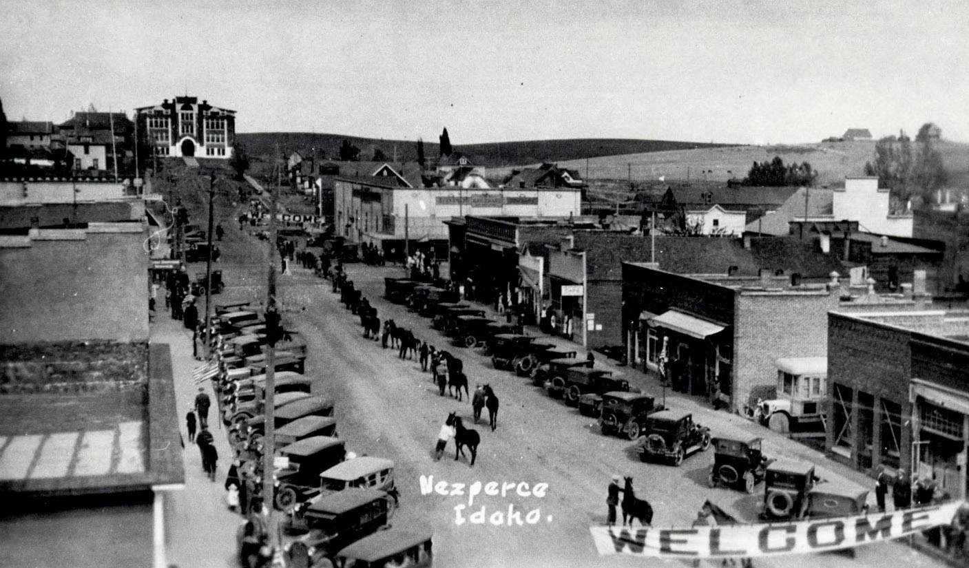 Street scene with horses, men and cars lined up [parade?]. Nez Perce