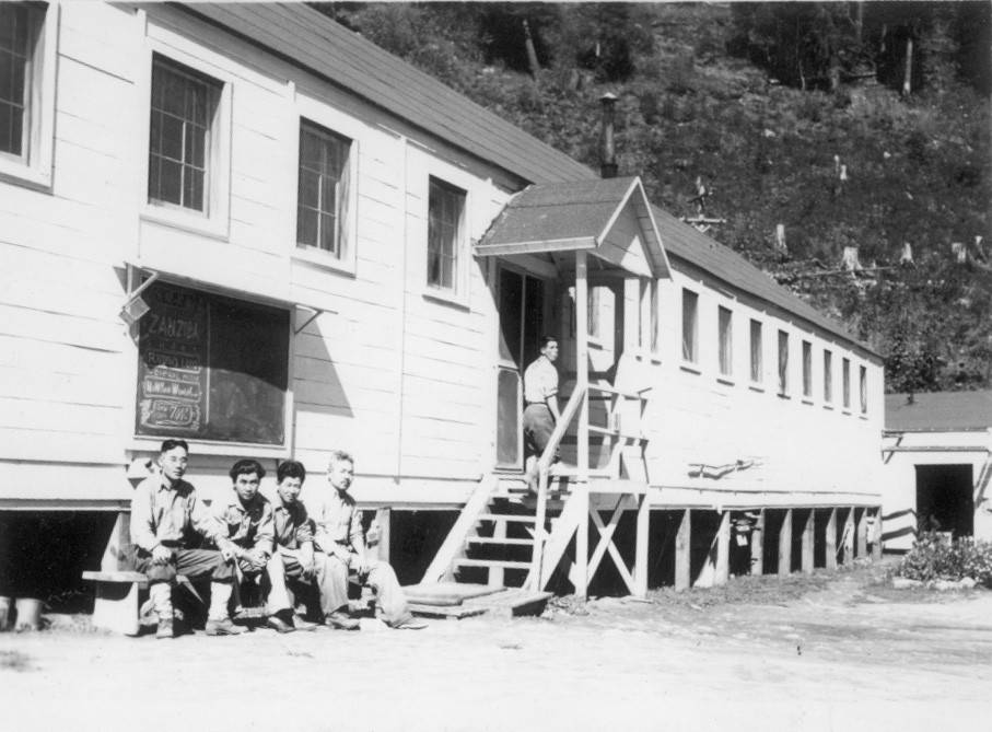 Men on bench outside building in Kooskia Kooskia Internment Camp