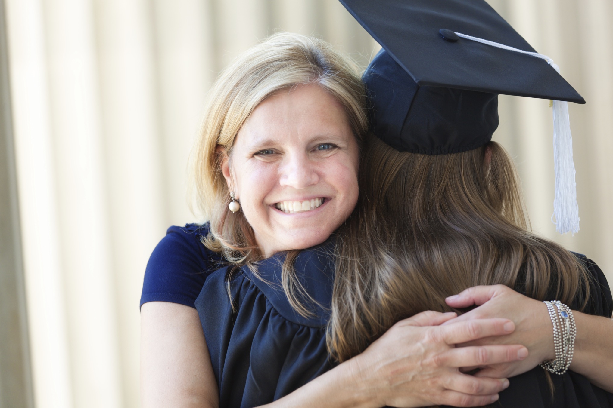 Happy Mother Congratulating Hugging Daughter in University Graduation