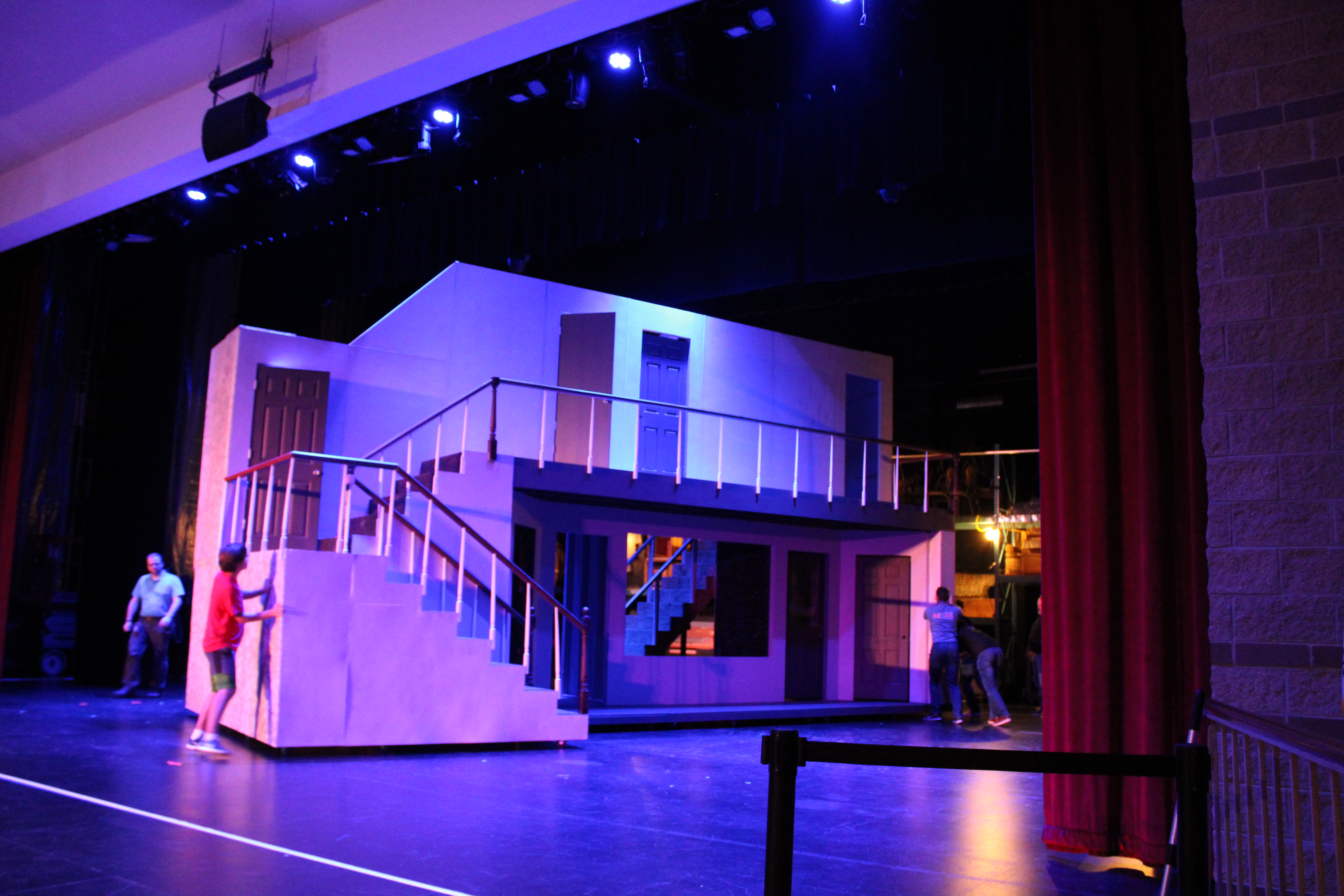 The stage crew moves the mobile set into place in the center of the stage. 