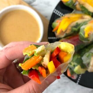 The inside of a fresh spring roll over dipping sauce and a platter of more rolls