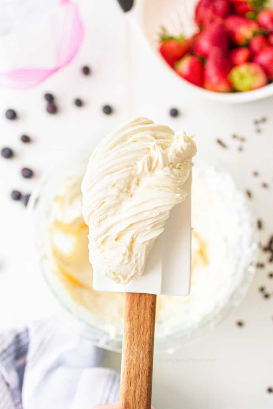 Thick cream cheese filling on a spatula over a bowl.