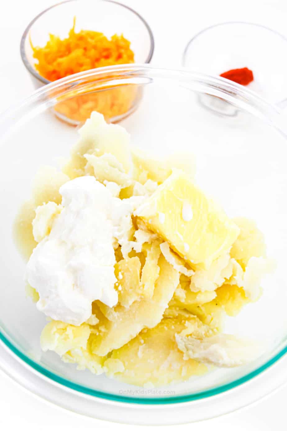 Potatoes with spices, butter, milk and sour cream before mixing in a bowl.