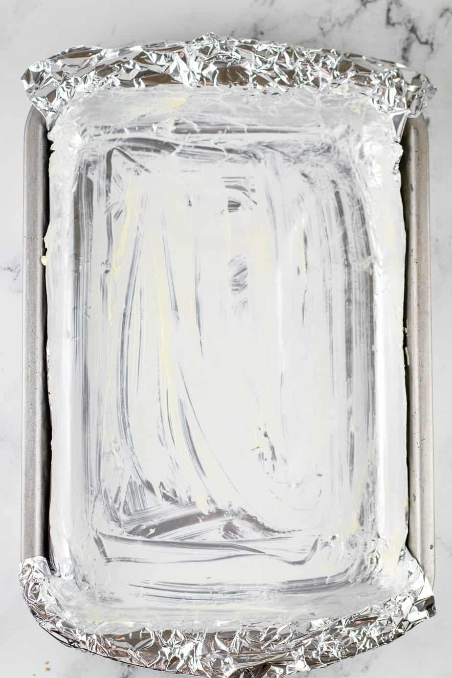 Large rectangular pan from overhead line with aluminum foil and greased on a counter from above.