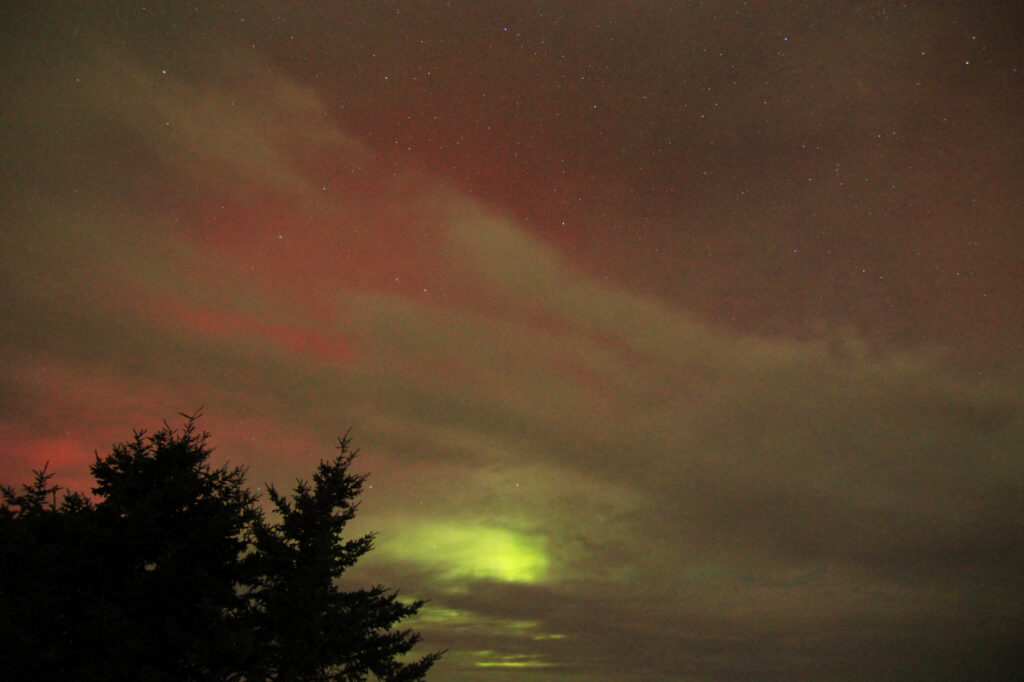 The aurora trying to peek through the clouds,a patch of very bright green