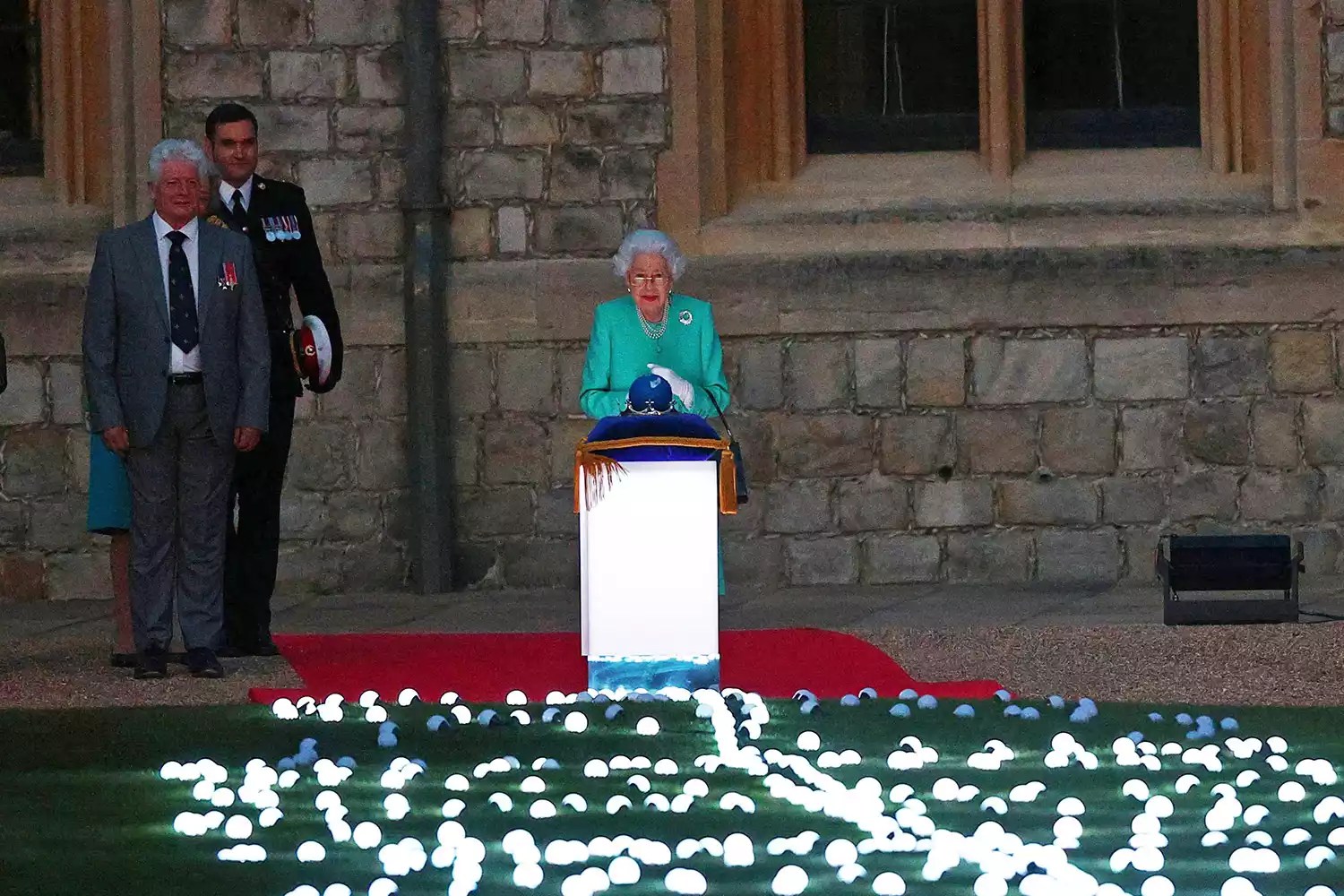 Britain&rsquo;s Queen Elizabeth II touches the Commonwealth Nations Globe to start the lighting of the Principal Beacon outside of Buckingham Palace in London, from the Quadrangle at Windsor Castle in Windsor, west of London, on June 2, 2022, as part of Platinum Jubilee celebrations. - The queen will be seen again at Windsor Castle, west of London, as more than 2,800 beacons are lit at Buckingham Palace and across the UK, including atop the four highest peaks, as well as on the Channel Islands, the Isle of Man, and British Overseas Territories. Flaming tributes will be seen in 54 Commonwealth capitals across five continents, from Tonga and Samoa in the South Pacific to Belize in the Caribbean. (Photo by Adrian DENNIS / POOL / AFP) (Photo by ADRIAN DENNIS/POOL/AFP via Getty Images)
