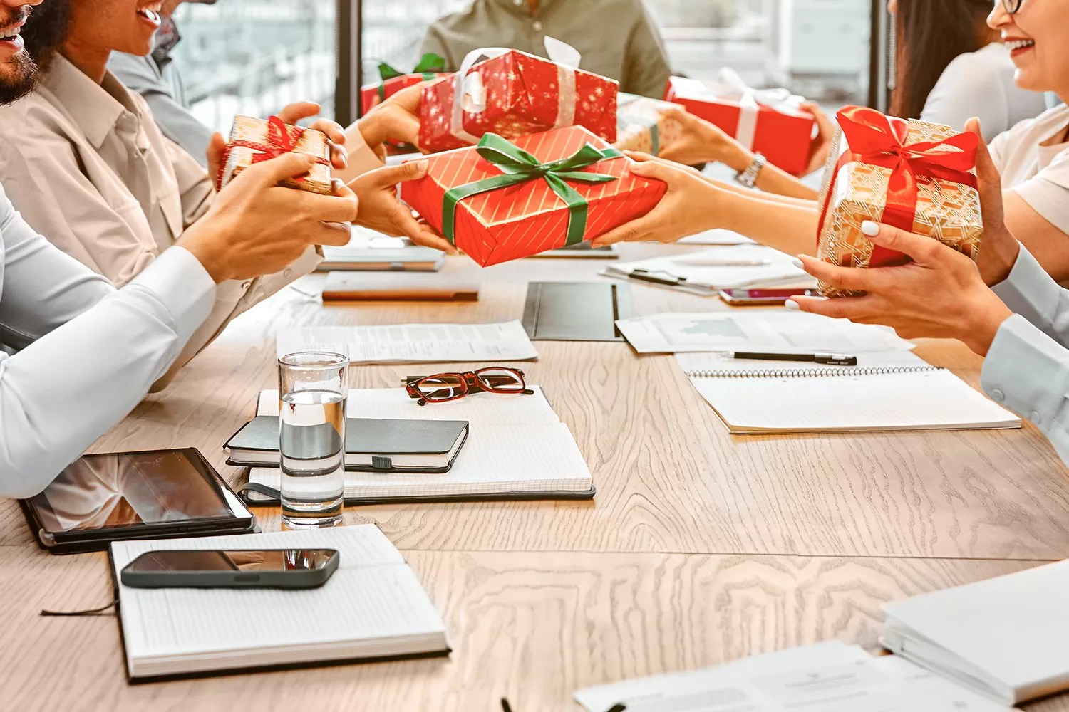 Christmas gift exchange at work. A group of happy business people are sitting at a table and exchanging gifts. Secret Santa.