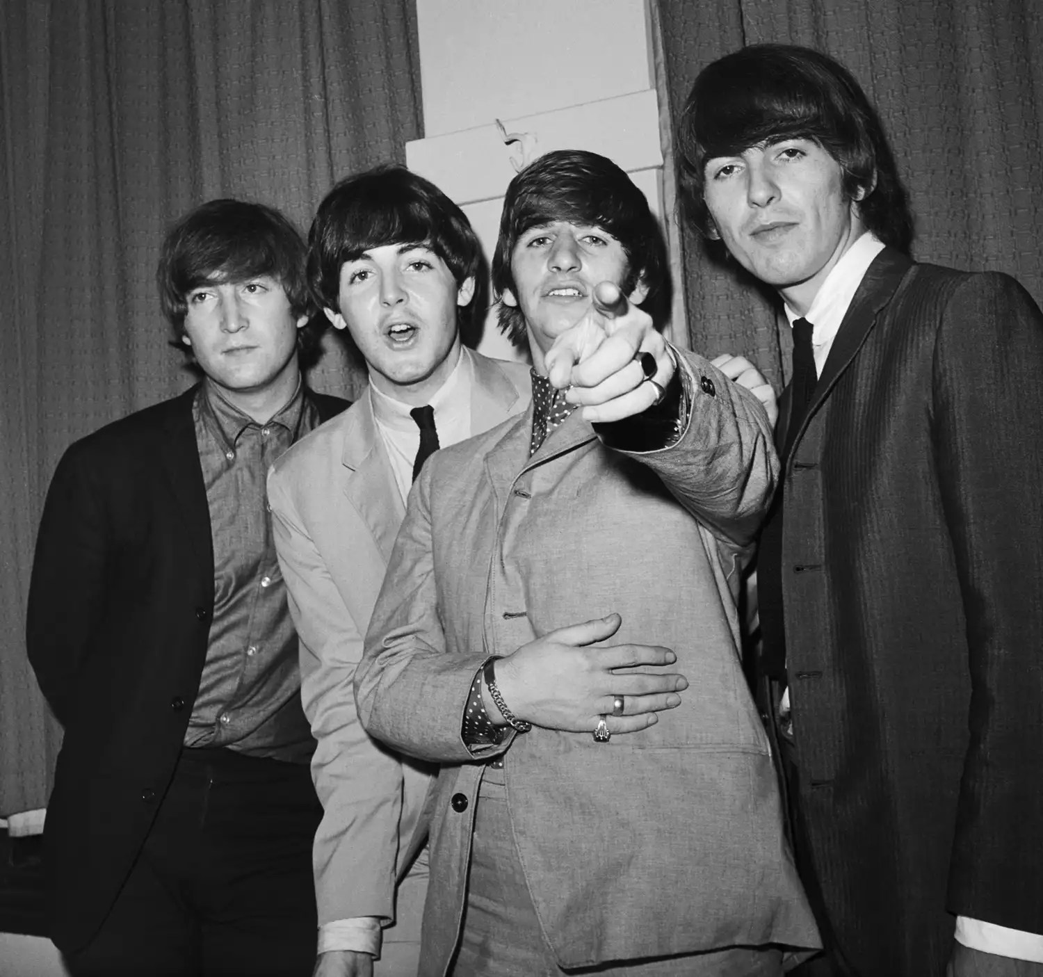 Ringo Starr points at the camera as fellow Beatles John Lennon, Paul McCartney, and George Harrison (L-R) stand beside him backstage at a charity performance at the Paramount Theater in Manhattan.