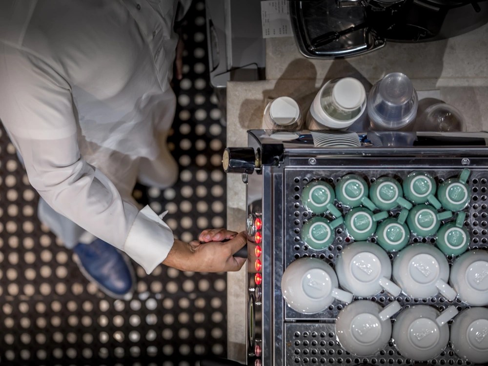 - Healthy Brew Hub An aerial view of cups on top of an espresso machine as a barista inserts a portafilter.