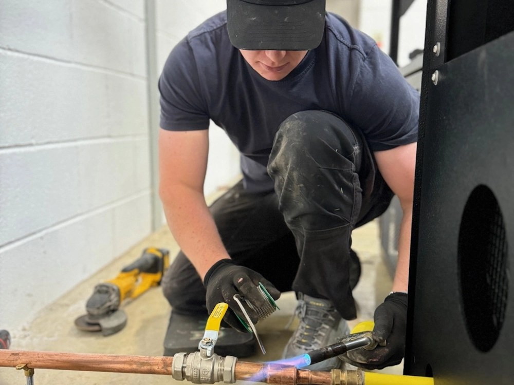 healthy brew hub a man uses a blowtorch to fit gas pipes on a coffee roaster