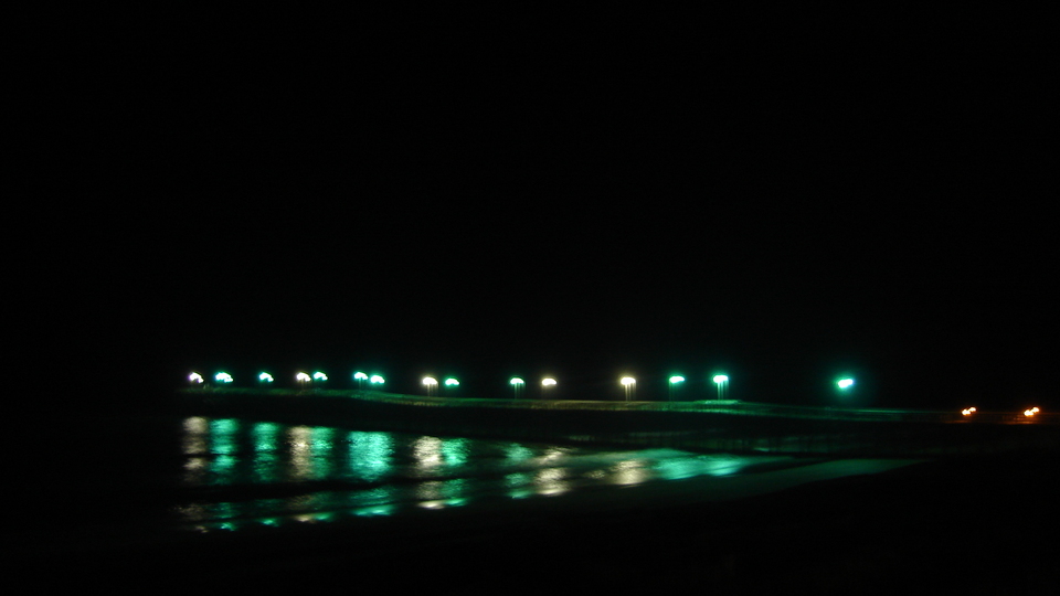 Topsail Beach, NC Pier lights reflecting on the beach by night at